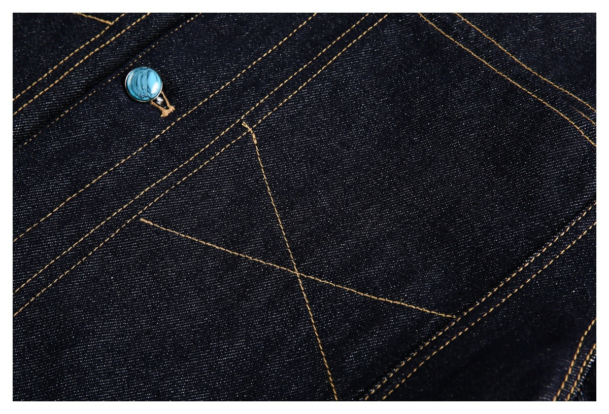 Close-up of dark indigo denim with gold stitching and a turquoise button.