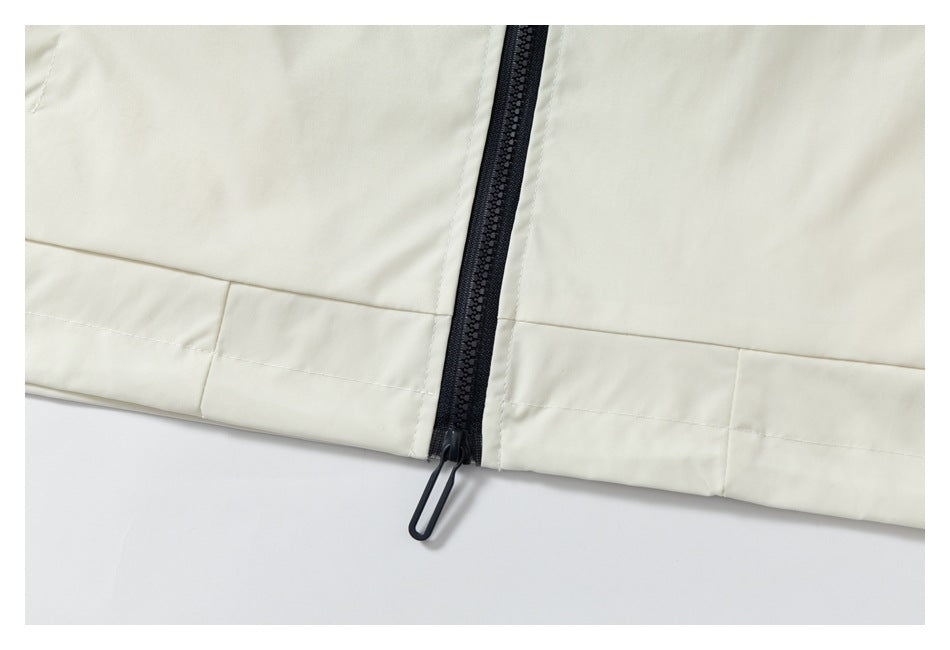 Close-up of the ivory jacket hem and black center zipper with an elongated pull.