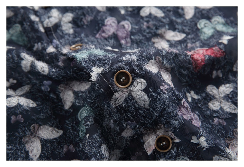 Close-up of brown buttons and textured butterfly-print fabric on the navy shirt.