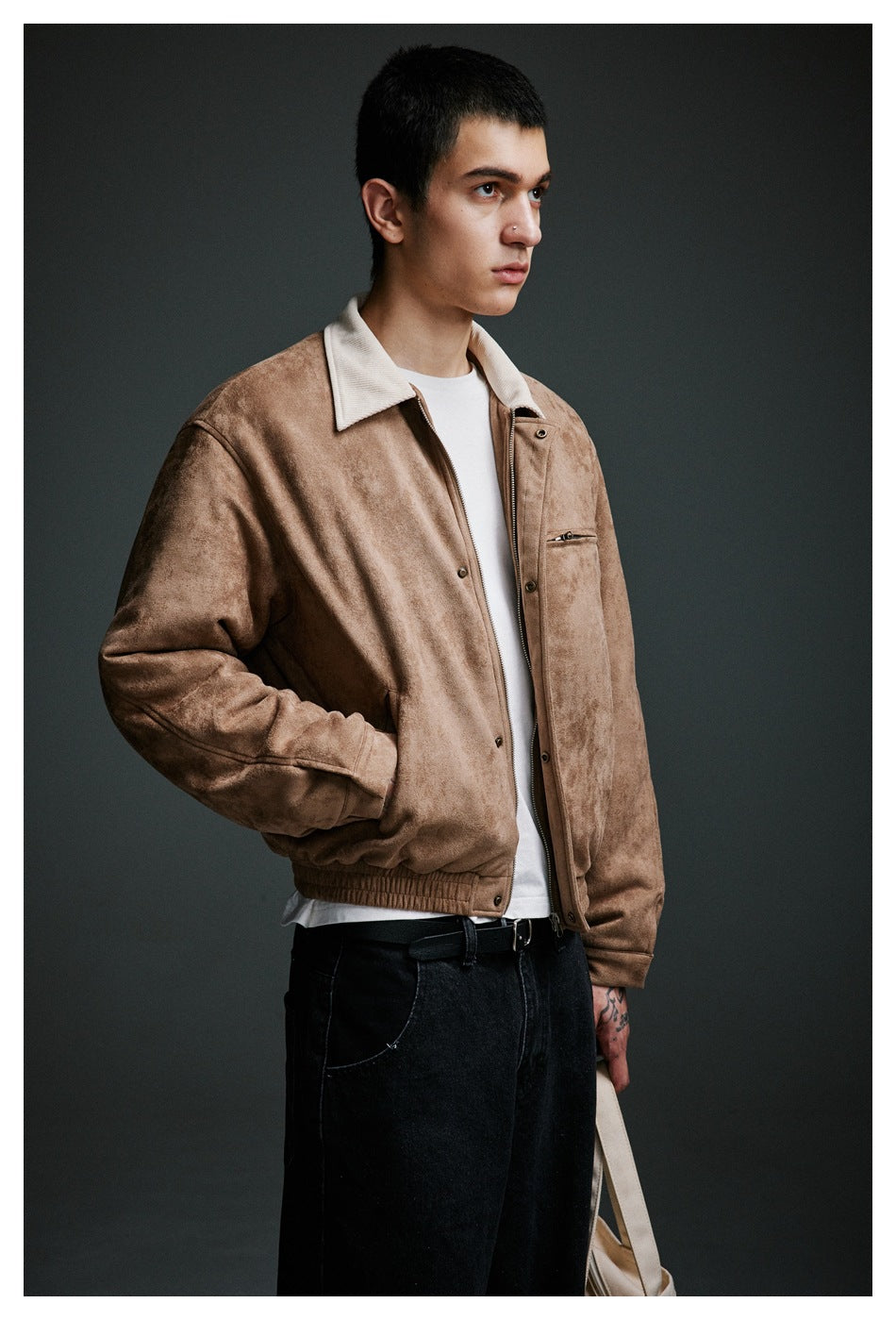 Three-quarter view of a man wearing a tan jacket with a cream collar, zip chest pocket and elastic hem.