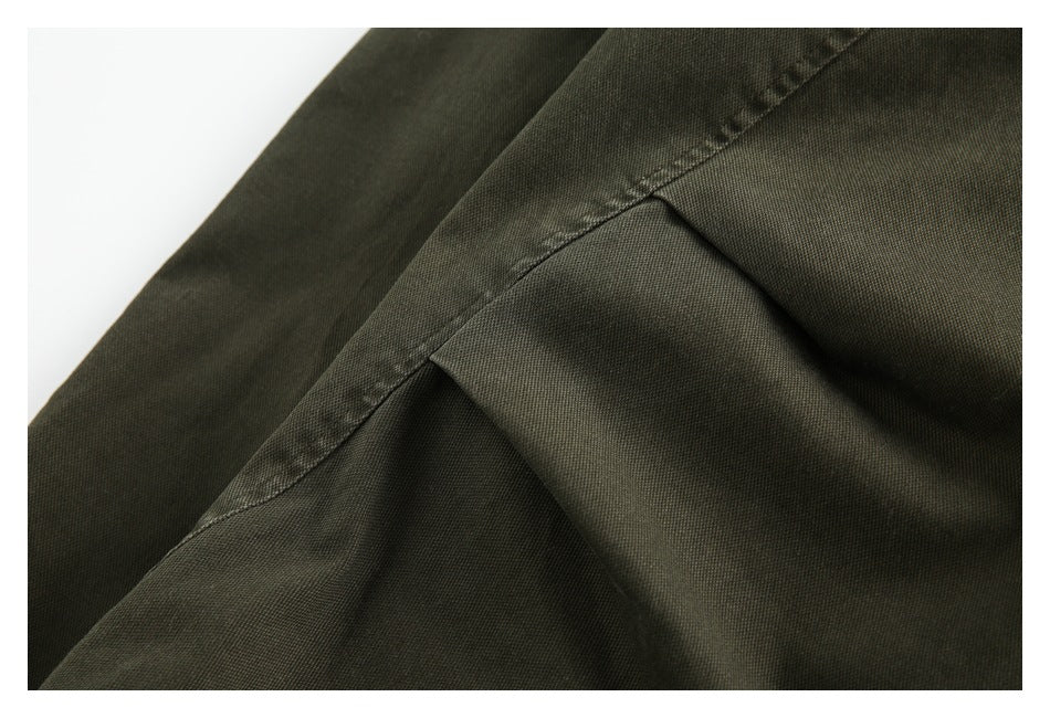 Close-up of an olive jacket seam and folded fabric panel.