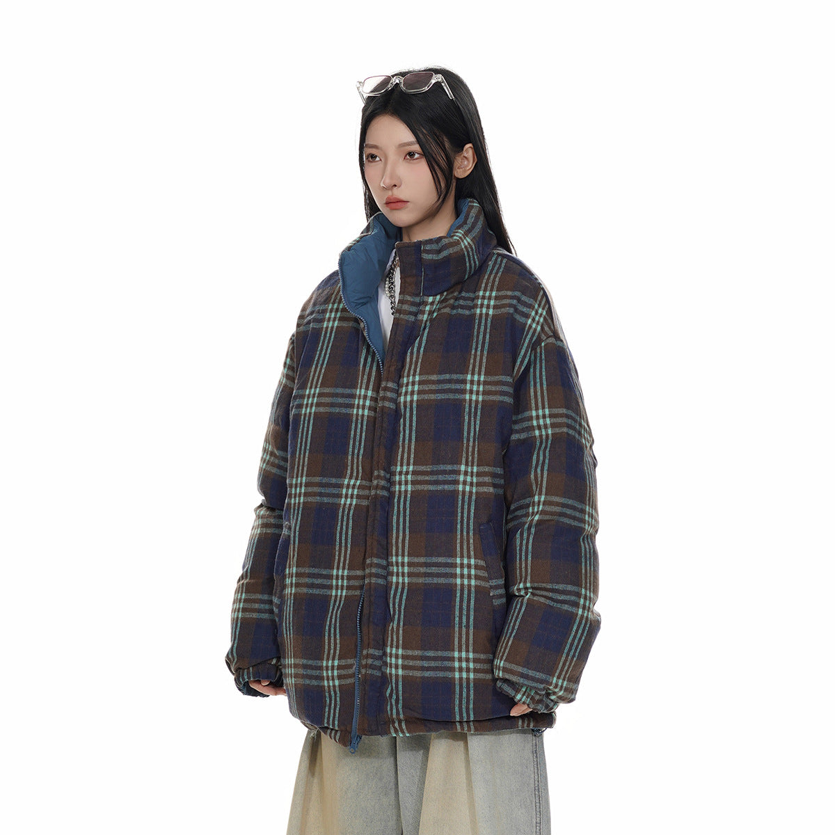 Model wearing an oversized navy and brown plaid jacket with turquoise stripes and a high blue-lined collar, front view.