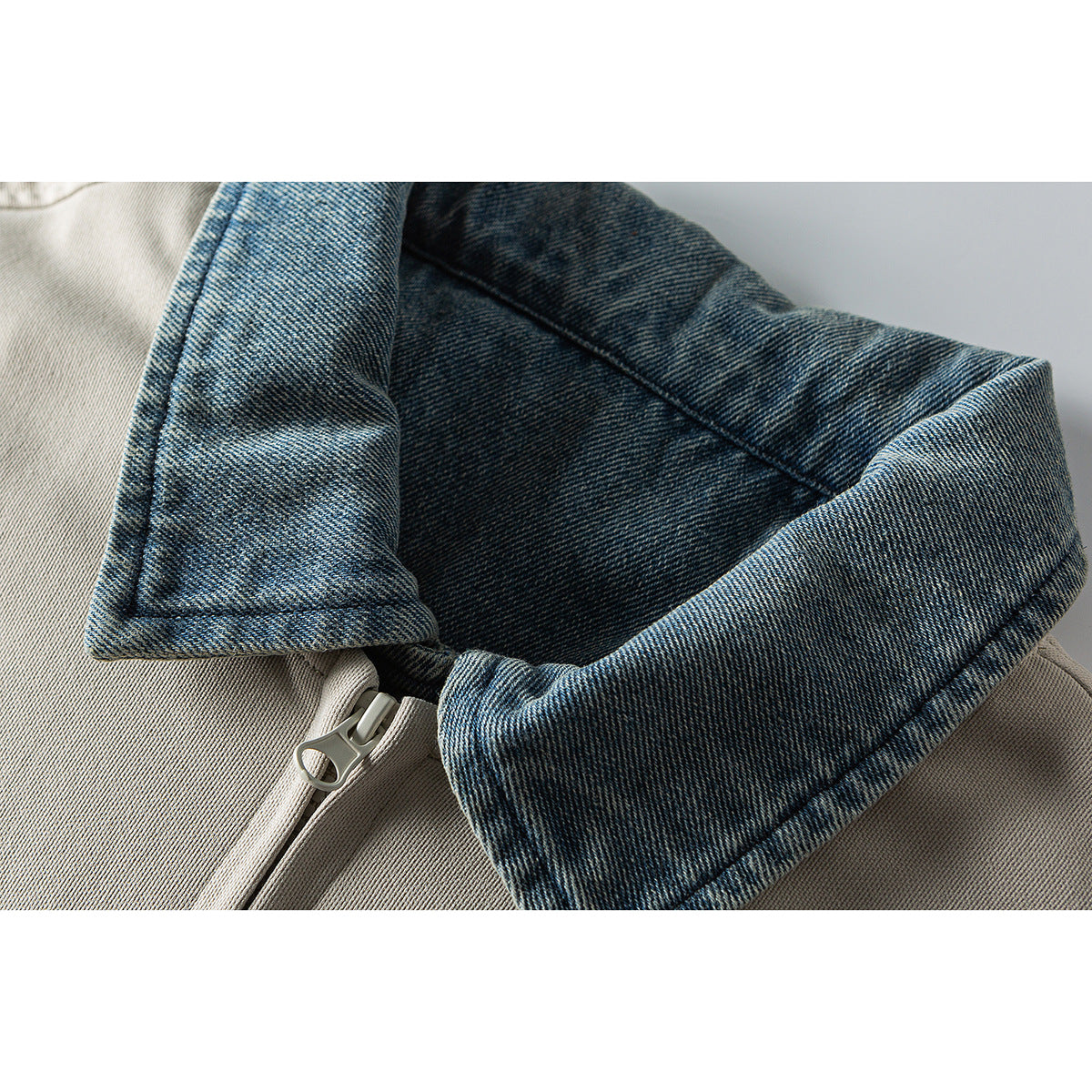 Close-up of a beige jacket with a blue denim collar and matching zipper.