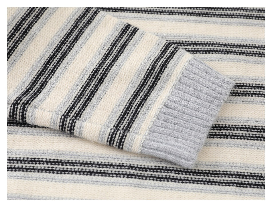 Close-up of a gray ribbed sleeve cuff against the cream sweater's black and gray stripes.