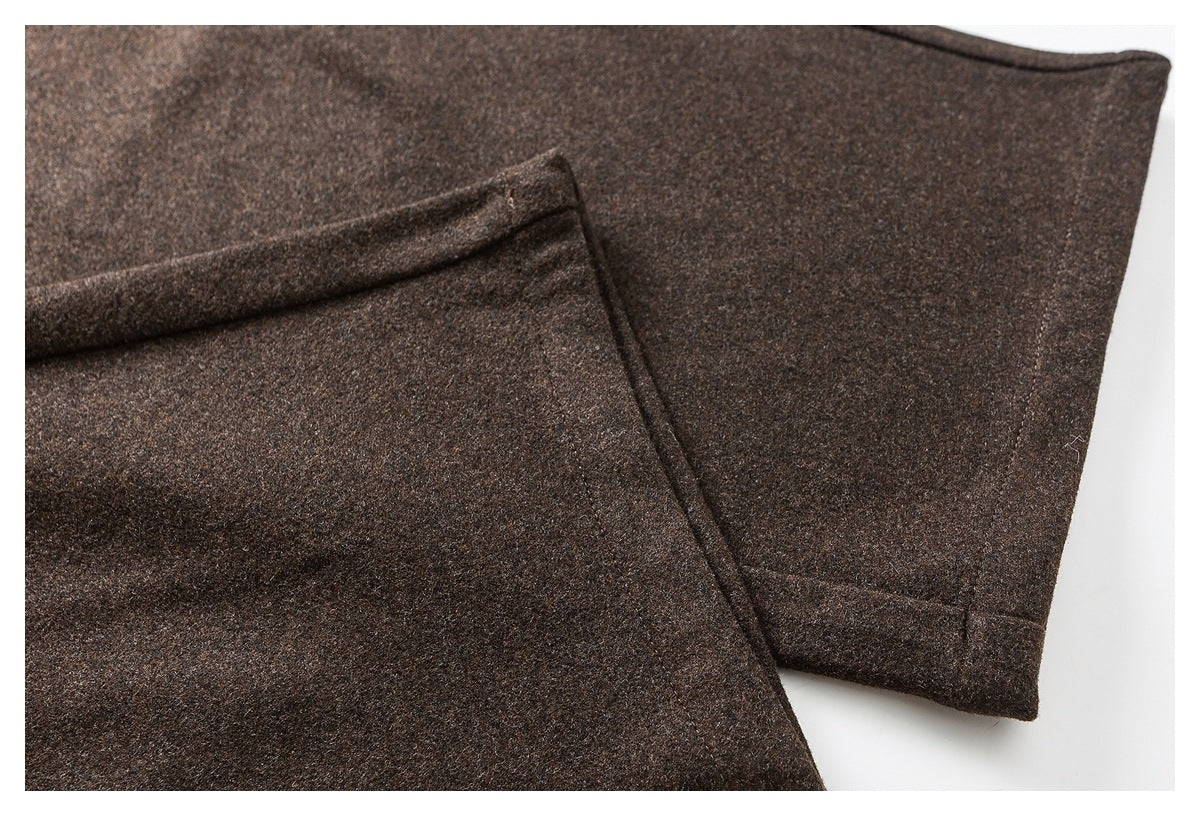 Close-up of dark brown pants showing a stitched pocket panel and finished edge.