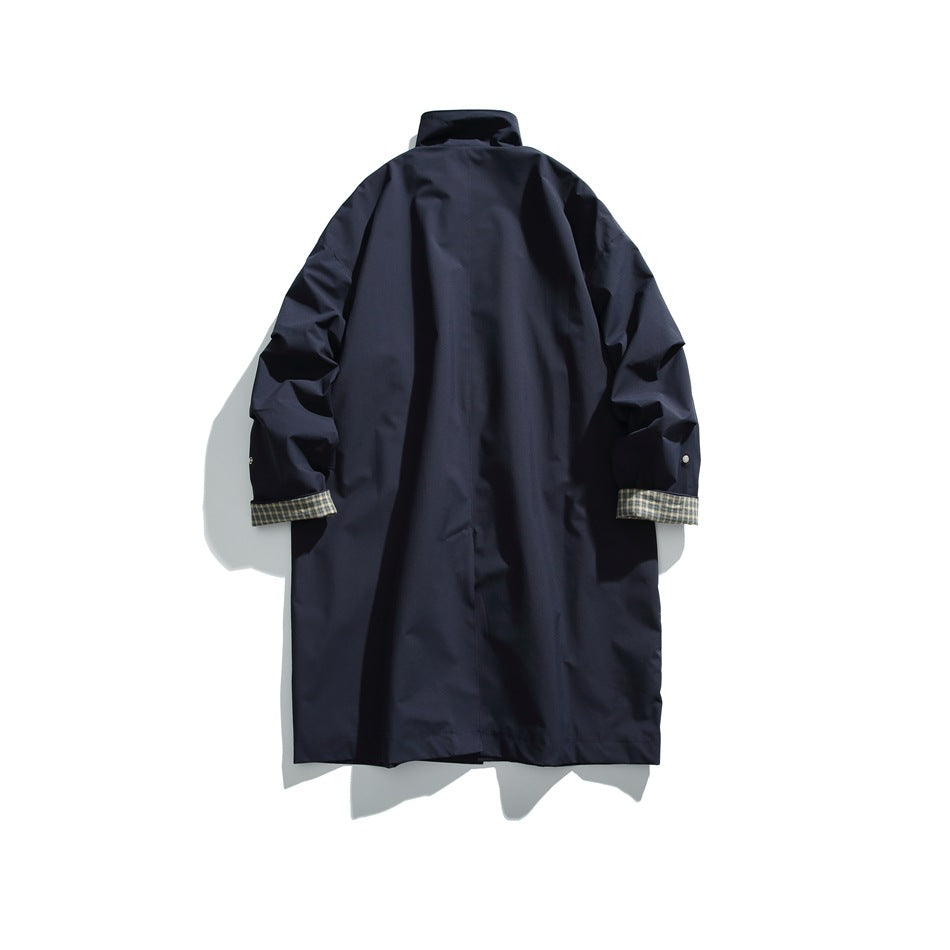 Back view of a dark navy long coat with a high collar and plaid lining visible at the turned-back cuffs.