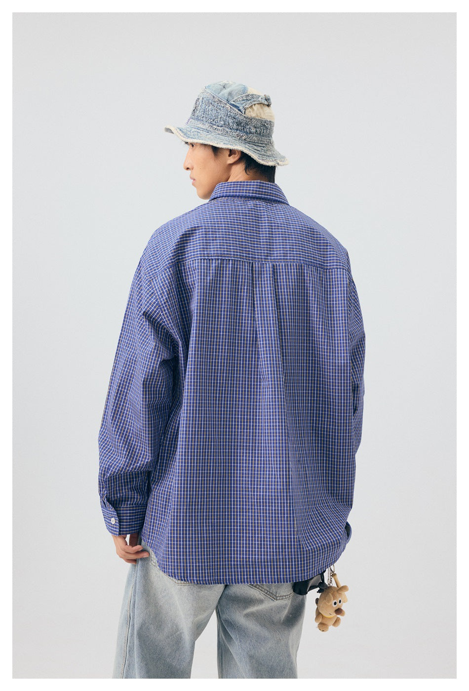 Back view of a model wearing a blue checked shirt with a gathered center pleat.
