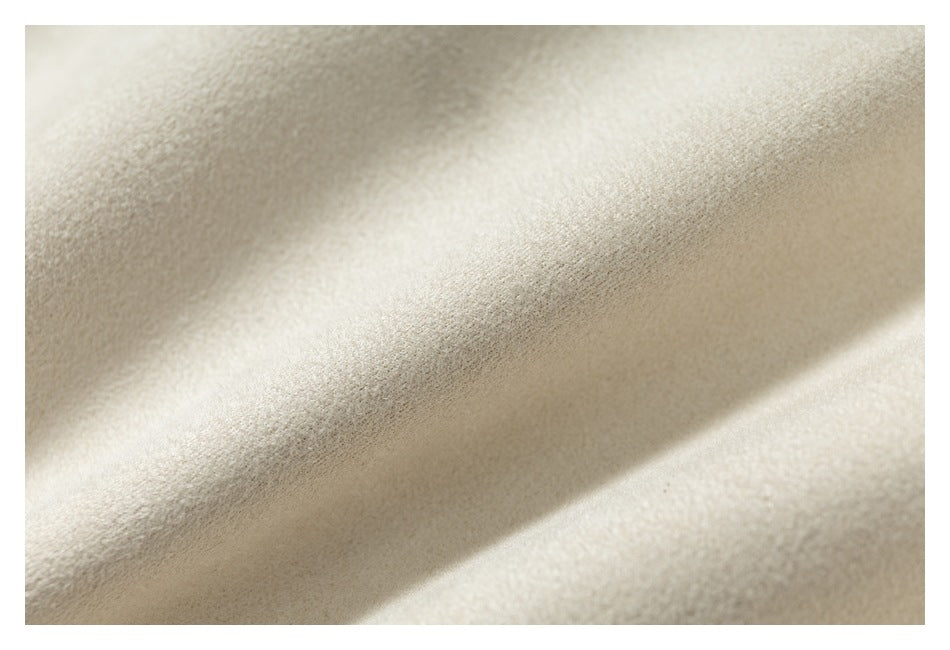 Close-up of softly textured ivory fabric with diagonal folds and warm shadows.