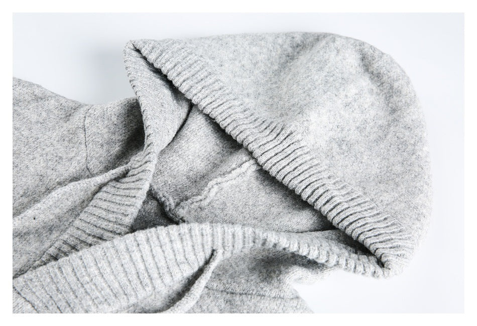 Close-up of light gray knitwear folded to show a wide ribbed edge and seams.