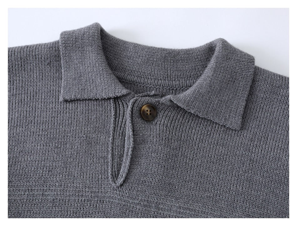 Close-up of a gray knitted sweater's pointed collar, one brown button, and short placket.