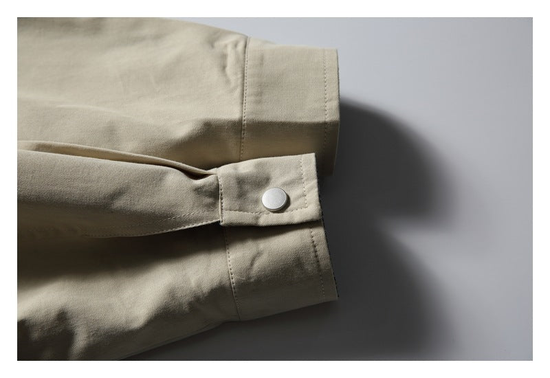 Close-up of a beige jacket sleeve cuff with a snap-button tab.