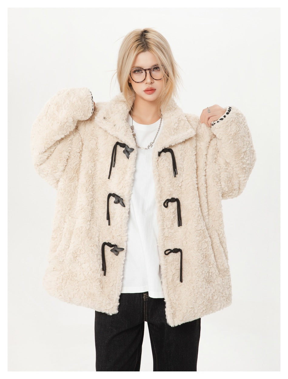 Front view of a model holding open the ivory textured coat to show its black toggle closures and roomy sleeves.