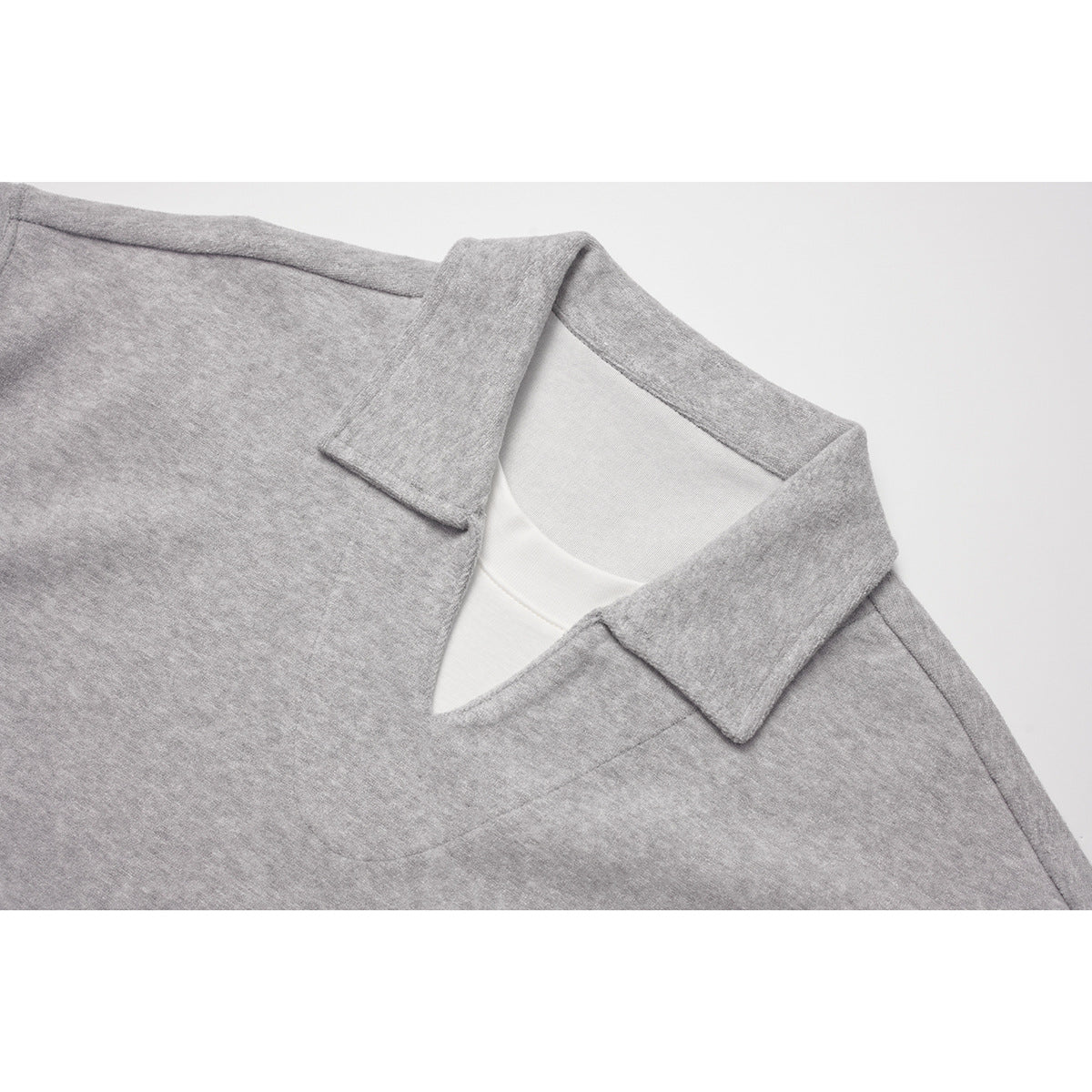 Close-up of the light gray top's pointed collar and V-shaped neckline, with a white layer visible underneath.