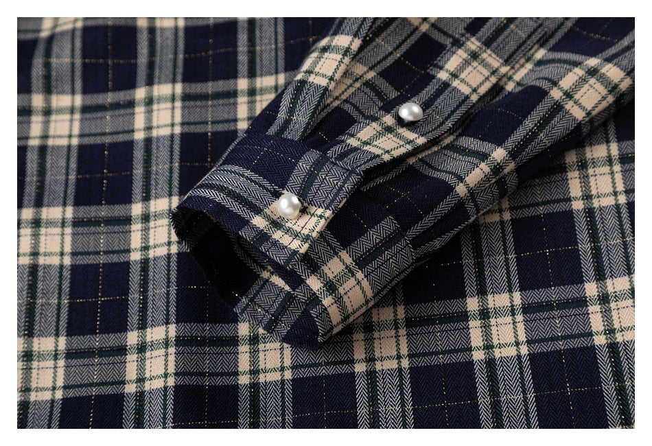 Close-up of a plaid shirt cuff and button placket with two pearl-like buttons.
