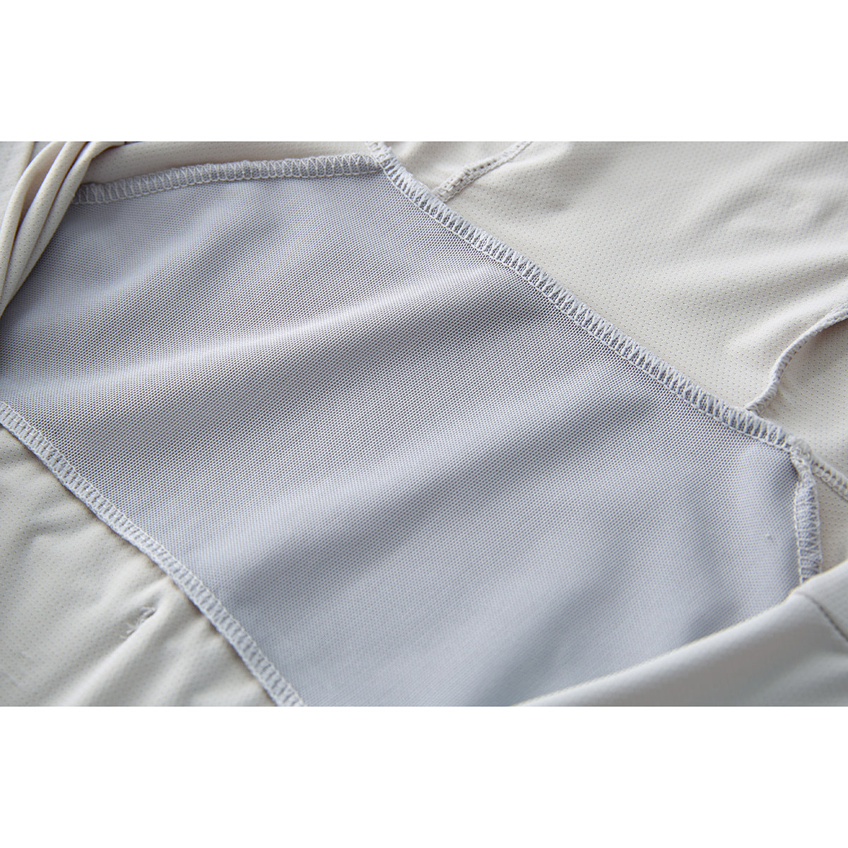 Close-up of the light gray jacket's inner mesh panel and overlocked seams.
