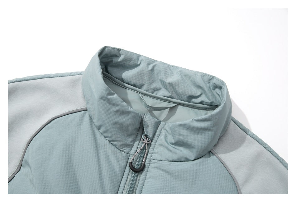 Close-up of a pale sage vest's stand collar, lining, curved shoulder seams, and zipper pull.