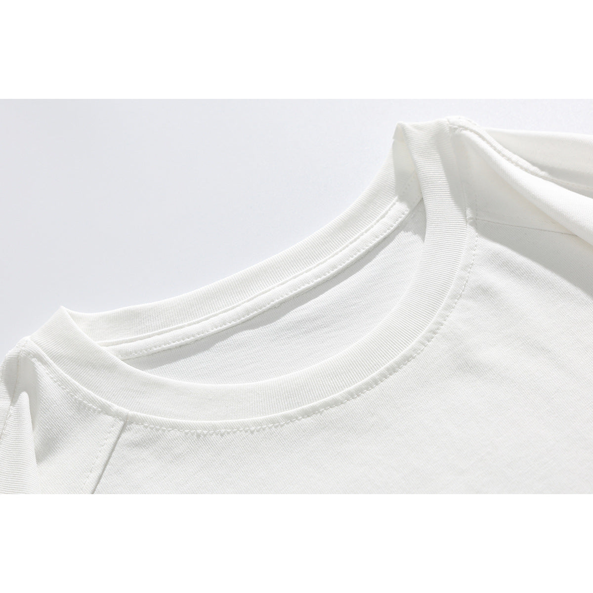 Close-up of a white T-shirt's ribbed crew neckline and shoulder seam.