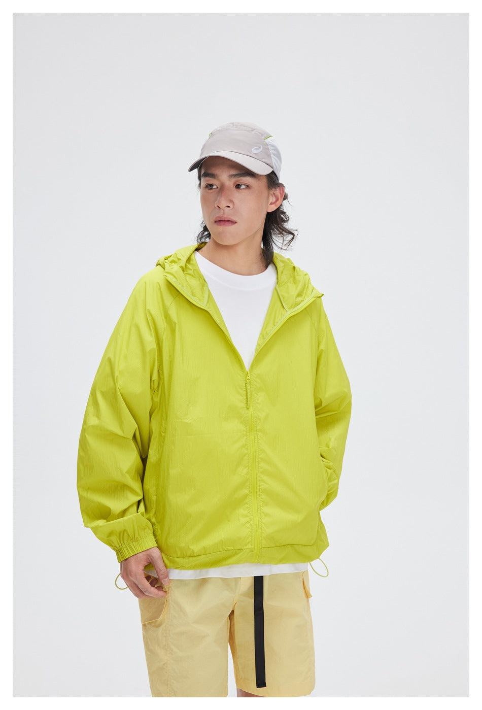 Model wearing a bright lime-green hooded zip jacket with pale yellow shorts.