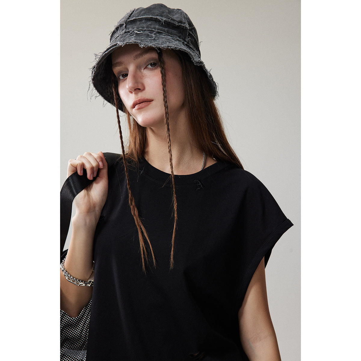 Front view of a model wearing a black sleeveless top with wide armholes and a small chest emblem.