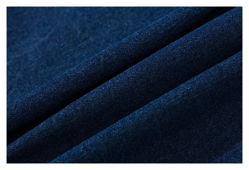 Close-up of dark blue denim fabric arranged in folds, showing its textured weave.