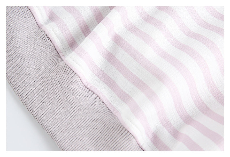 Close-up of a seam joining pale gray ribbed fabric to pink-and-white wavy striped fabric.