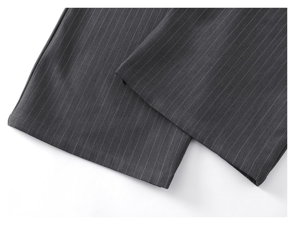 Close-up of the hems of charcoal trousers with fine light pinstripes.