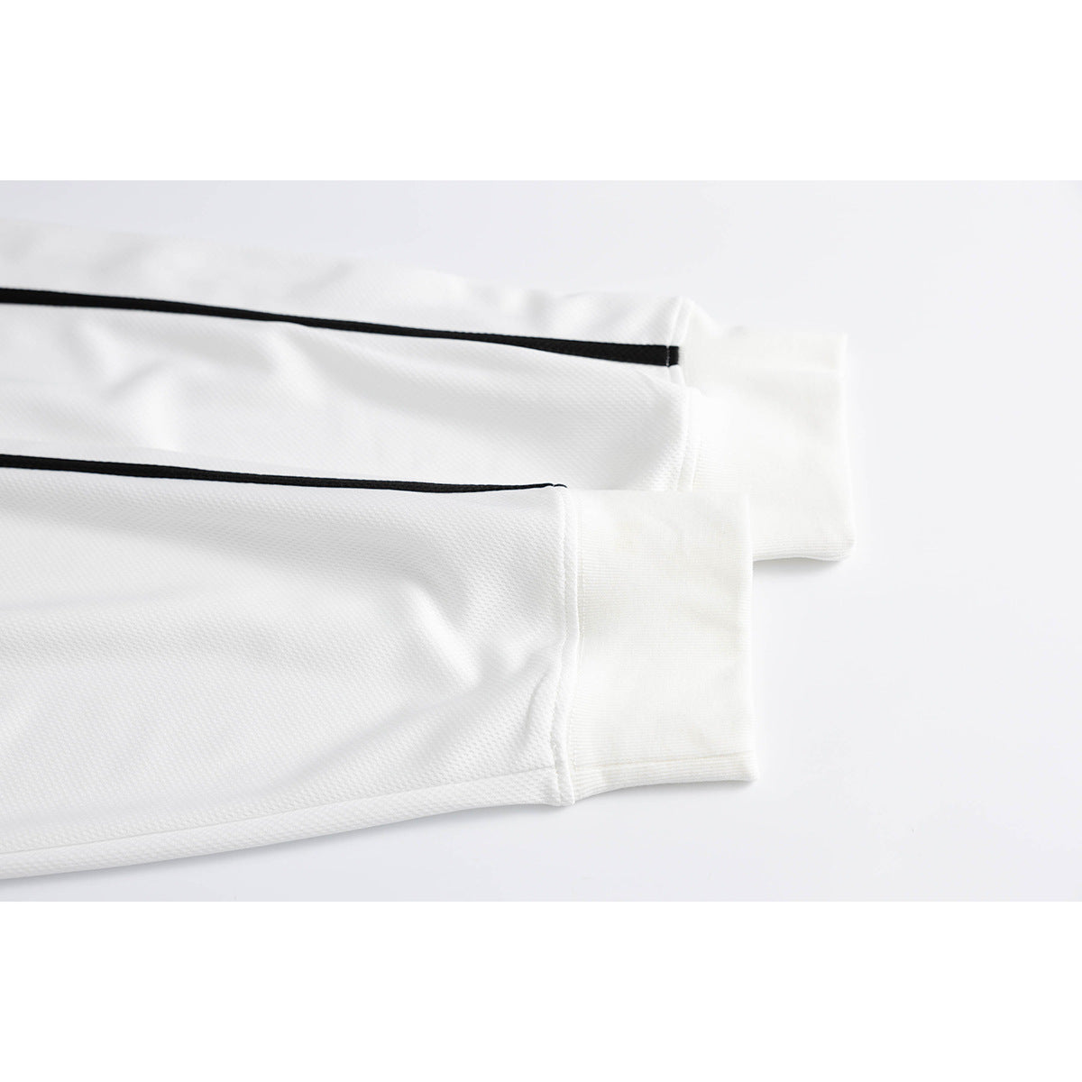 Close-up of a white jersey sleeve with black piping and a wide white cuff.