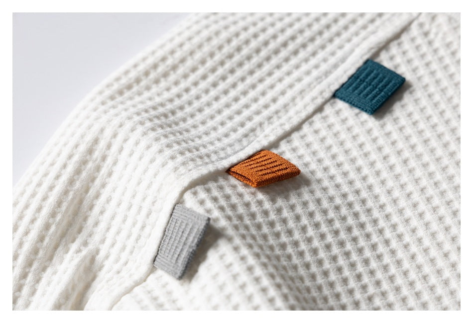 Close-up of ivory waffle-knit fabric with teal, rust and gray fabric tabs.