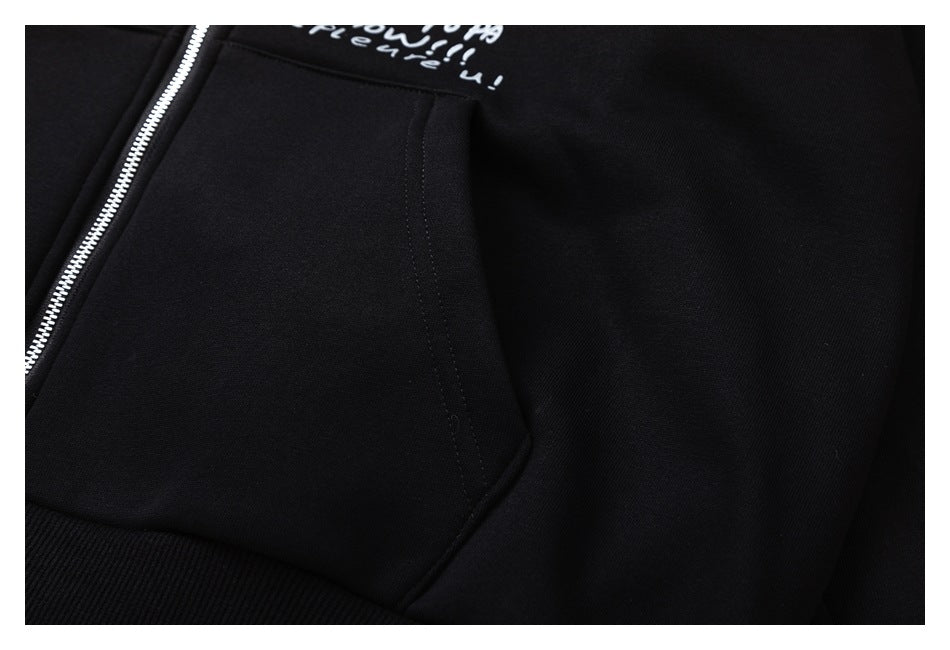 Close-up of a black hoodie kangaroo pocket, ribbed hem, and silver zipper.