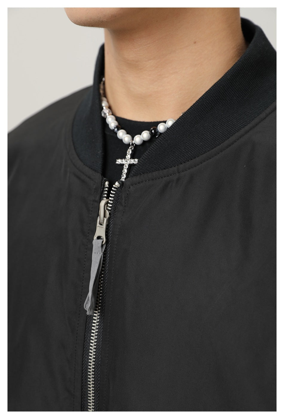 Close-up showing the black bomber jacket's ribbed collar, silver zipper and neckline.