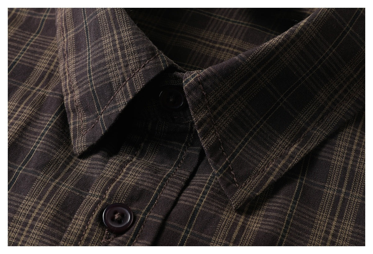 Close-up of the pointed collar and dark buttons on a dark brown plaid shirt.