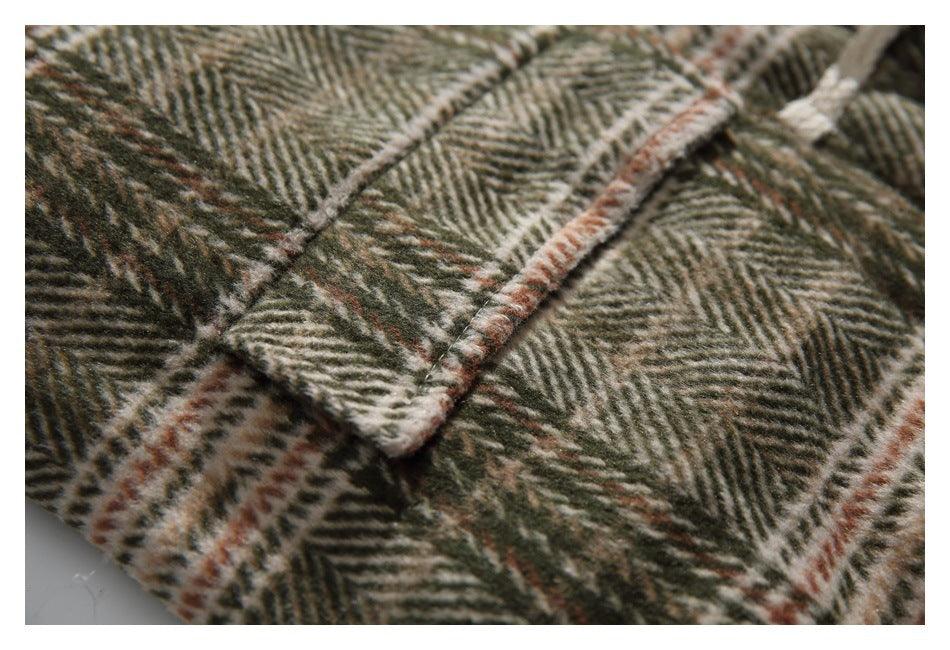 Close-up of a stitched flap edge against the coat's olive, cream, and rust plaid.