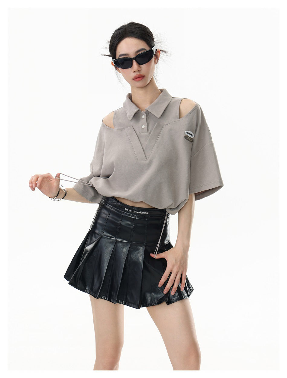 Model wearing a taupe cutout-shoulder polo top with a V-shaped front panel and drawstring hem, shown with one drawstring