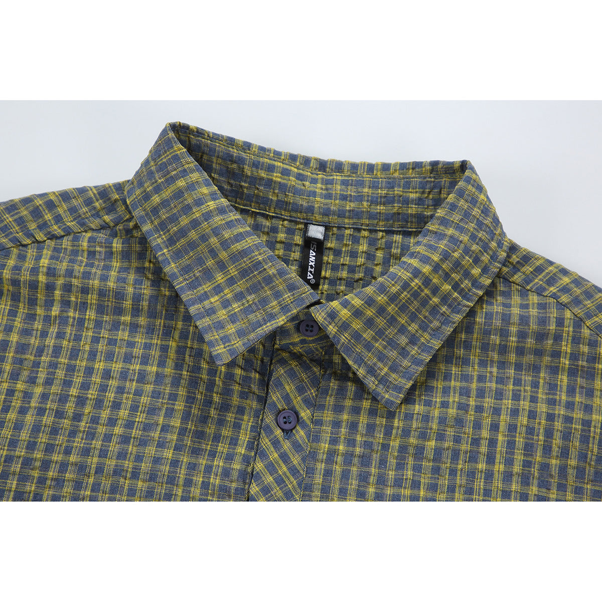Close-up of a blue-gray and mustard plaid shirt collar, buttons, and sewn-in black neck label.