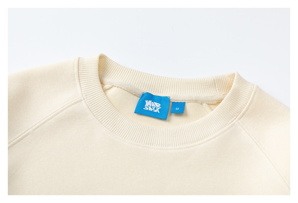 Close-up of a cream sweatshirt's ribbed crew neckline and blue size and brand tags.