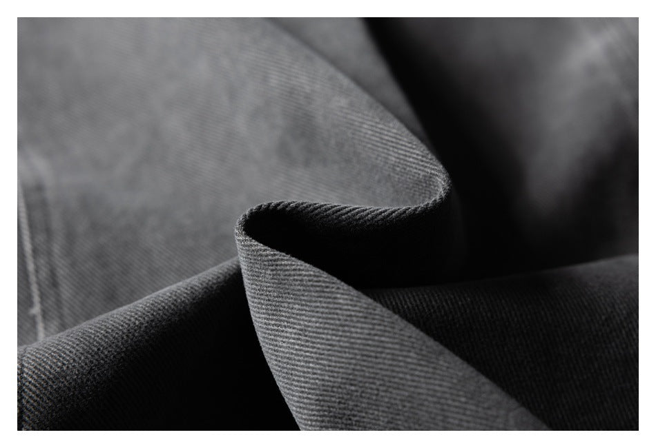 Macro view of charcoal jacket fabric folded to show its surface and drape.