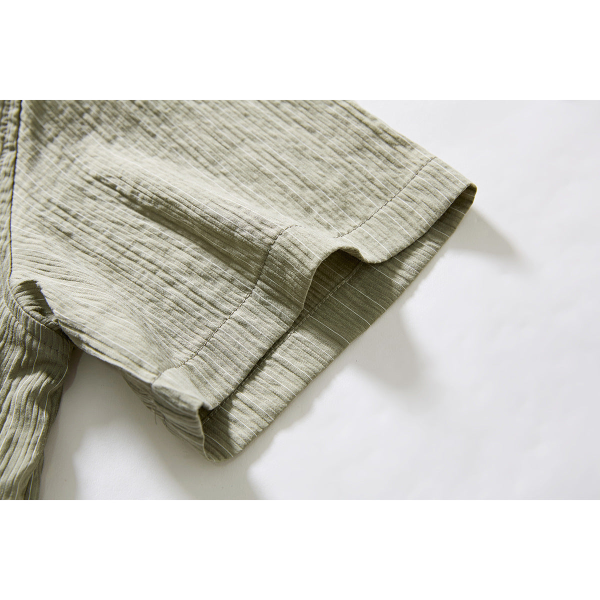 Close-up of the olive-gray shirt’s short sleeve and stitched cuff edge.