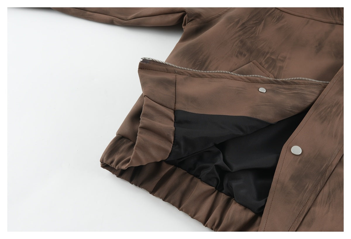 Close-up of a brown jacket opened to show black lining, zipper, and snap fasteners.