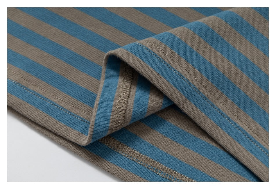 Close-up of a turned garment hem showing blue and taupe stripes and overlock stitching.