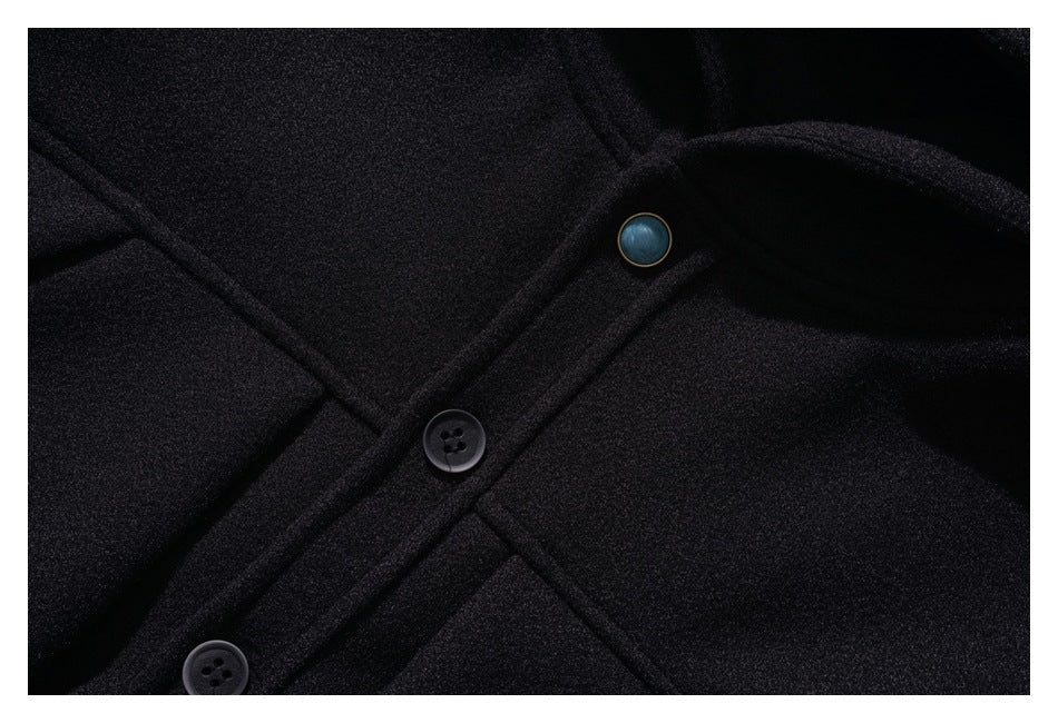 Close-up of a black coat’s front placket with dark buttons and a blue-toned metal snap.
