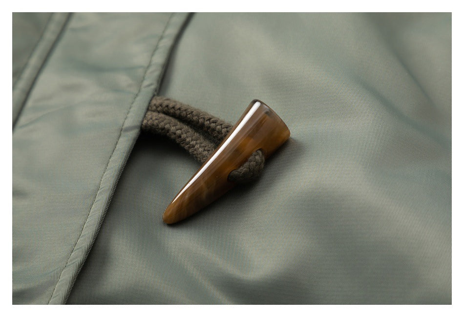 Close-up of a brown toggle and braided loop on olive-gray fabric.