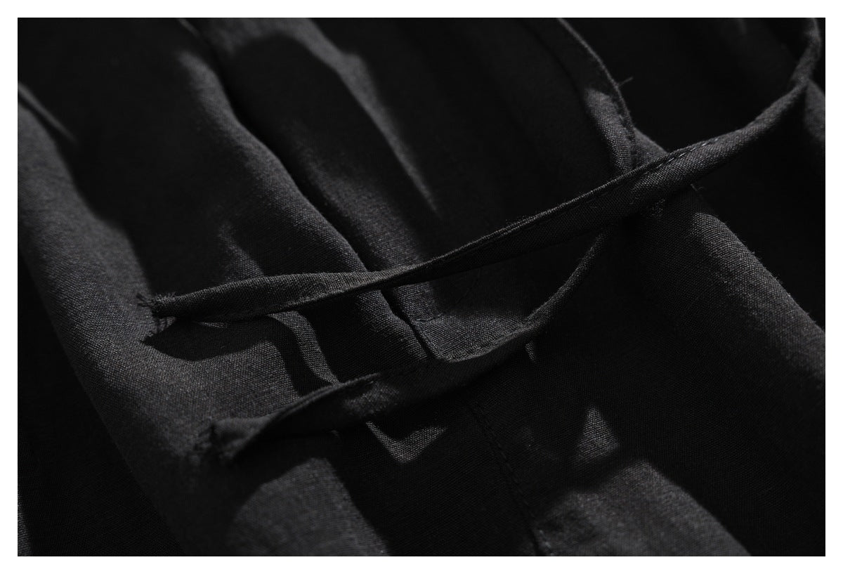 Close-up of black garment fabric with narrow fabric loops crossing over a stitched seam.