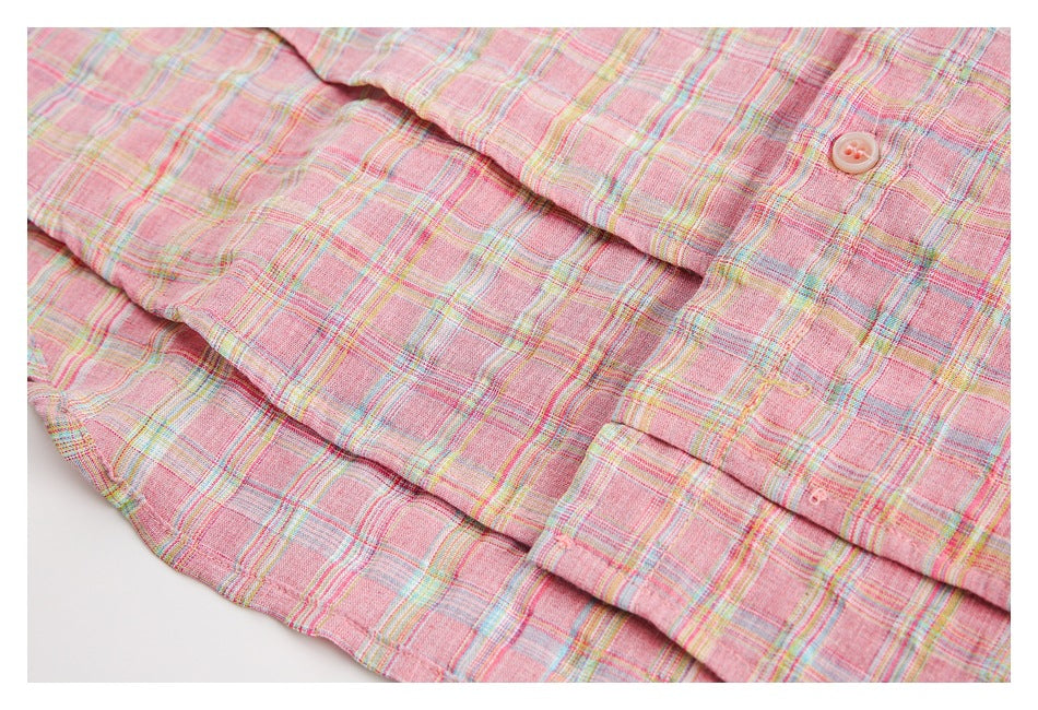 Close-up of a pink multicolor plaid garment showing a button and overlapping fabric panels.