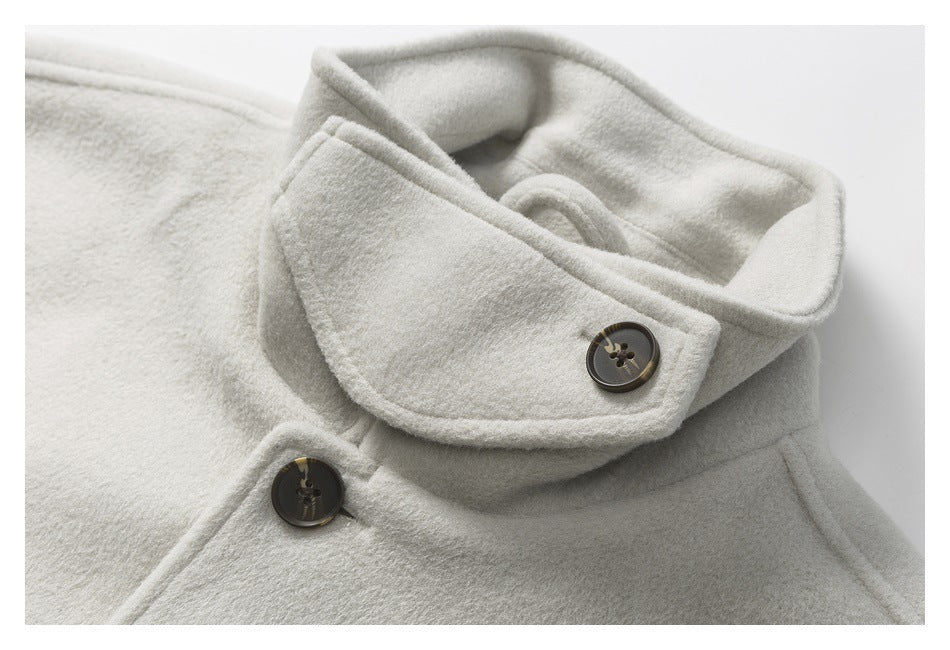Close-up of an ivory coat’s oversized folded collar and dark buttons.