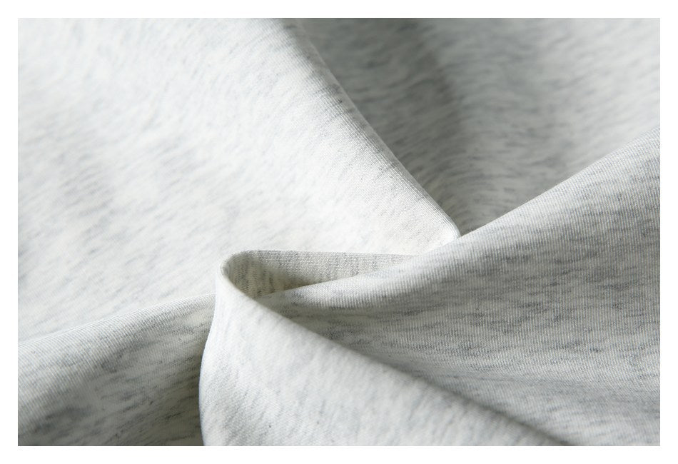 Close-up of pale heather gray knit fabric folded to show a ribbed edge.