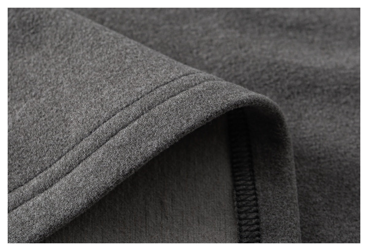 Close-up of a gray garment's folded edge and dark overlock stitching.