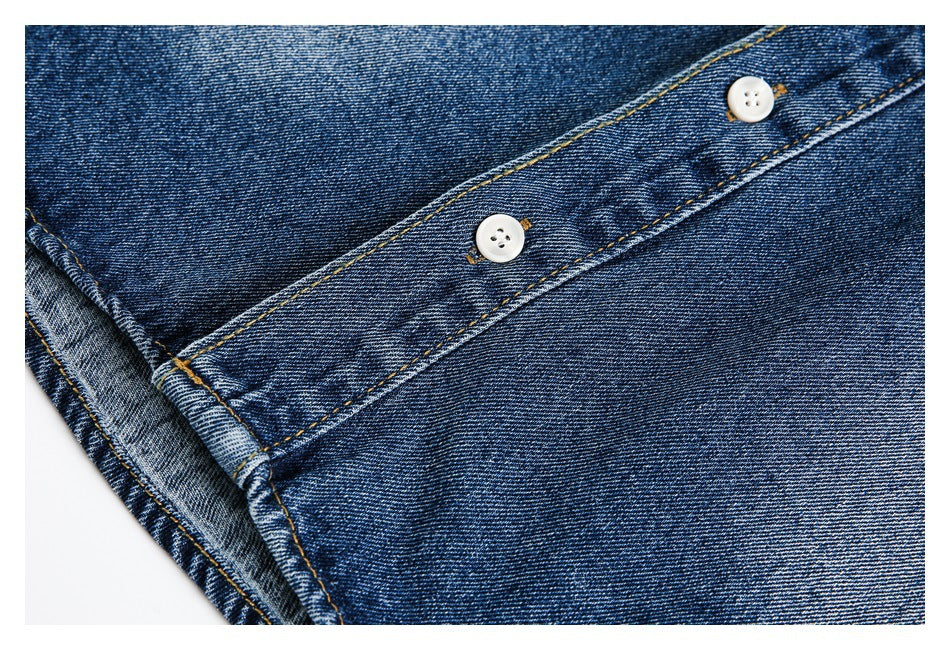 Close-up of dark blue denim fabric with a stitched placket and two white buttons.
