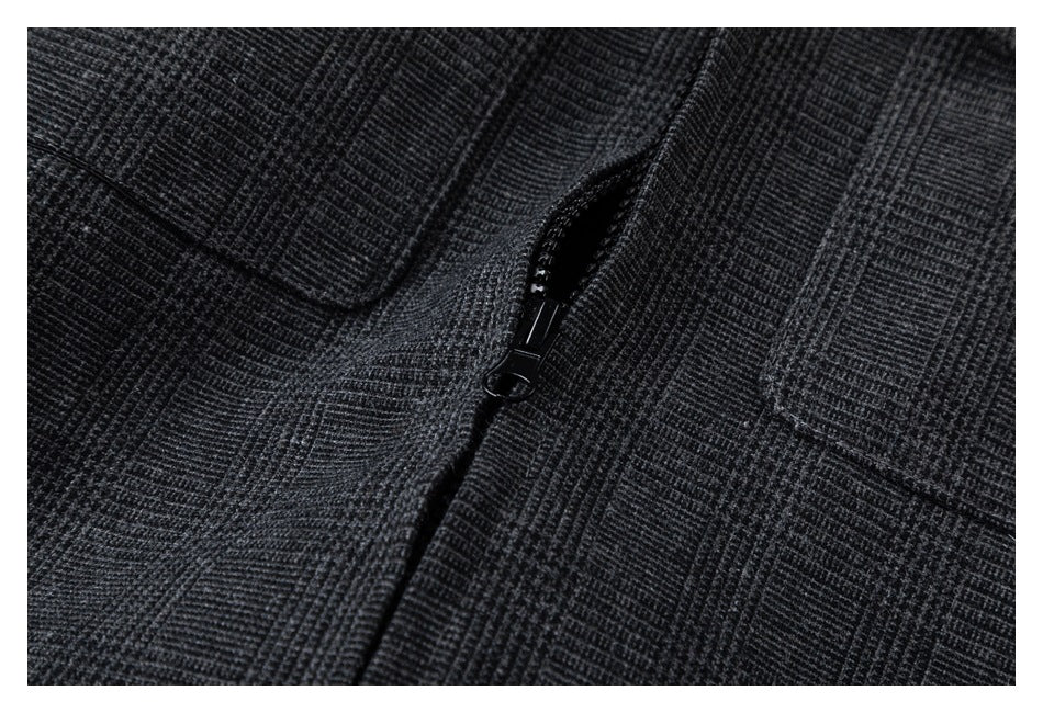 Close-up of the black zipper between panels of charcoal plaid jacket fabric.