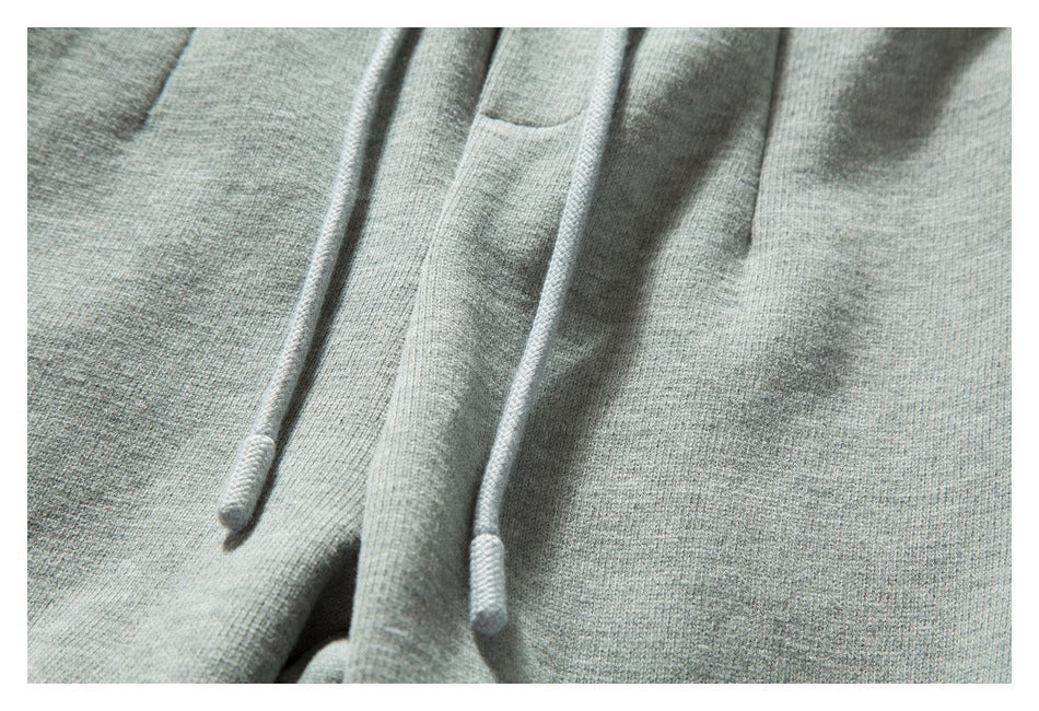 Close-up of light gray knit joggers with matching drawstrings and a small front pocket.