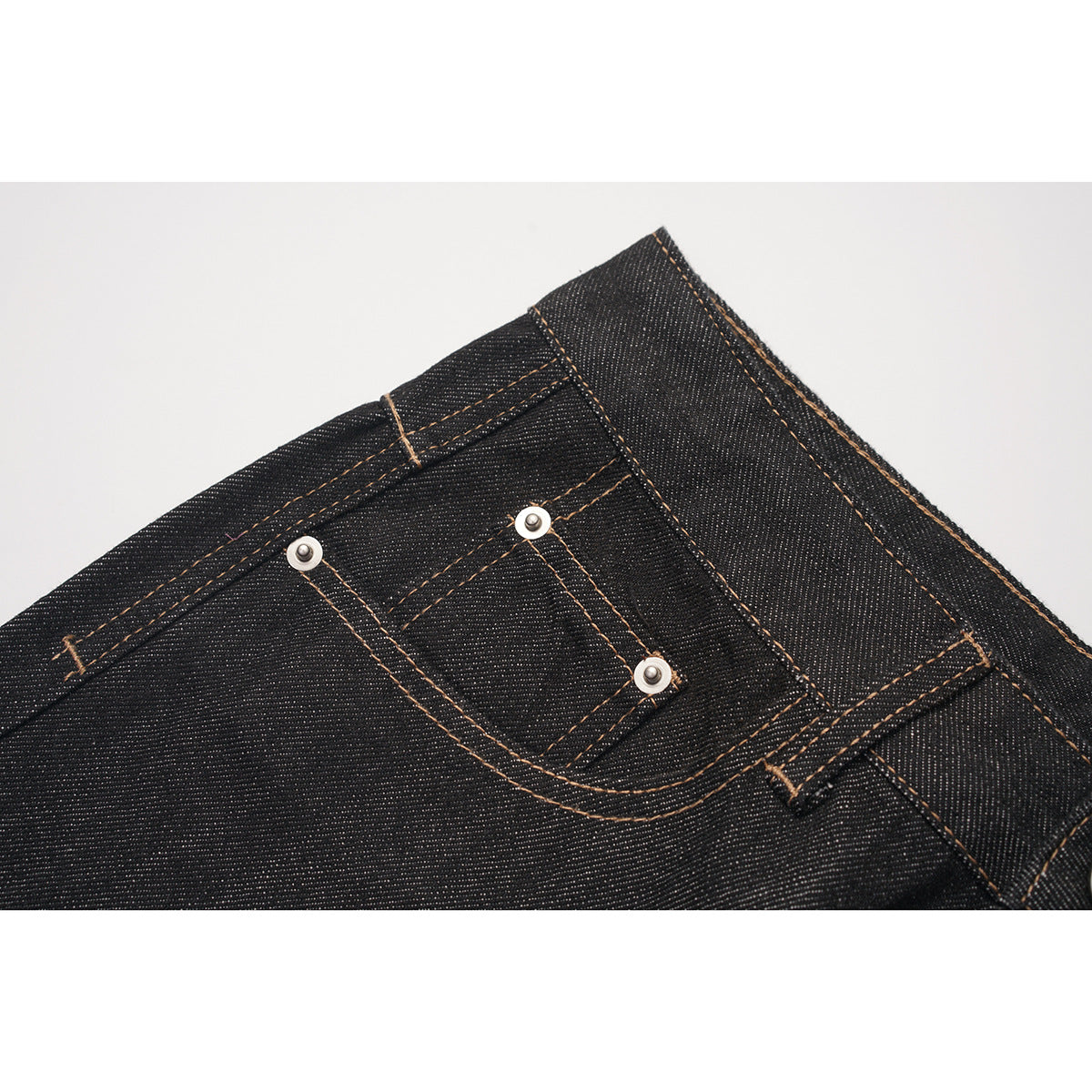 Close-up of black jeans showing the small front coin pocket, rivets, belt loop, and contrast stitching.